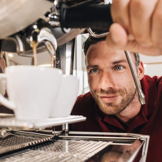 Ein Techniker von Kaffee Partner beobachtet wie zwei Tassen Kaffee zubereitet werden