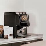 Barista-suprema-mit-kaffeebohnen-und-topping