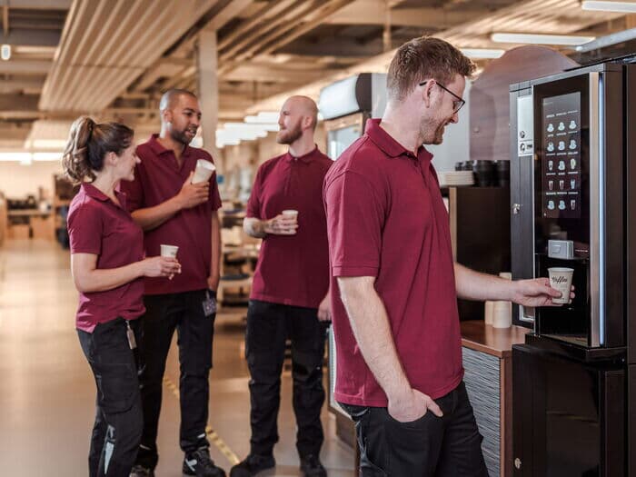 Team-kaffeepause-gruppe-mitarbeitende-kaffeemaschine