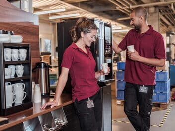 Zwei Mitarbeitende in der Fertigung geniessen während einer kurzen Pause einen Kaffee aus der BARISTA Duro.
