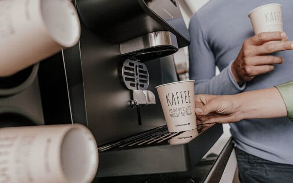 Coffee to go Becher im Becherspender eines Kaffeevollautomaten