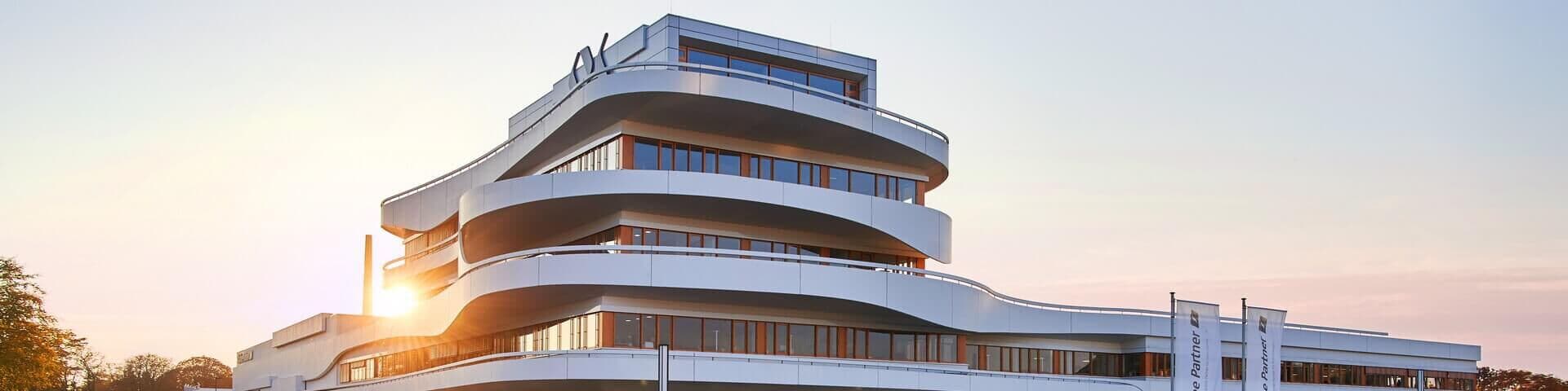 Modernes Firmengebäude von Kaffee Partner mit geschwungener Architektur bei Sonnenuntergang