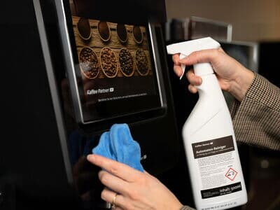 Kaffeevollautomat wird mit Reiniger und Tuch für optimale Hygiene gereinigt