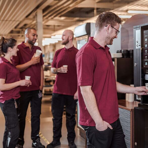 Team-kaffeepause-gruppe-mitarbeitende-kaffeemaschine