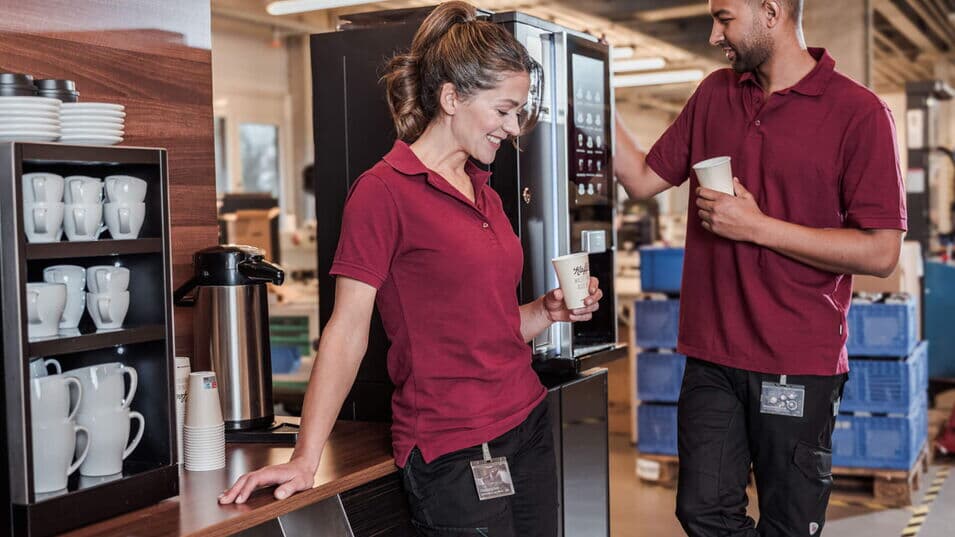 Zwei Mitarbeitende in der Fertigung geniessen während einer kurzen Pause einen Kaffee aus der BARISTA Duro.