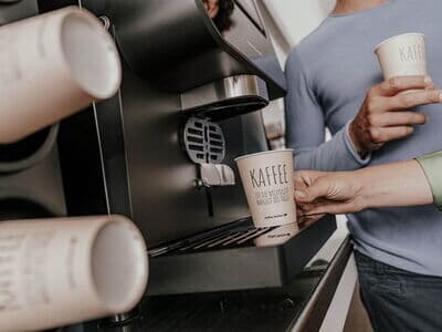 Coffee to go Becher im Becherspender eines Kaffeevollautomaten