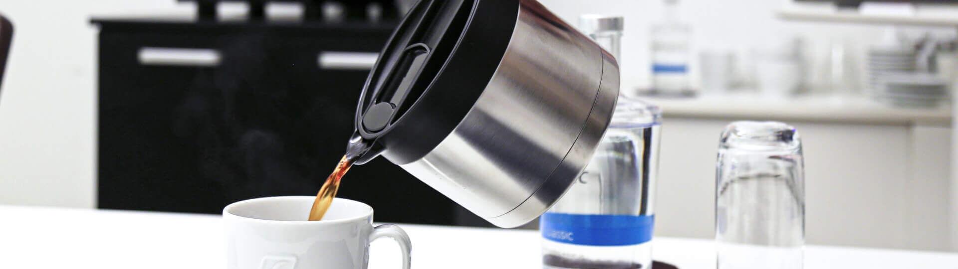 Kaffee wird aus Thermoskanne in Tasse gegossen