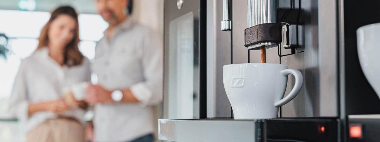 Frischer Kaffee läuft aus Kaffeevollautomat in eine weiße Tasse